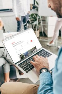 cropped shot of young businessman using laptop with airbnb website on screen